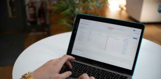 Hands typing on a laptop with a spreadsheet on screen.