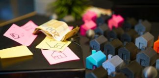 Miniature houses with euro banknotes and sticky notes.