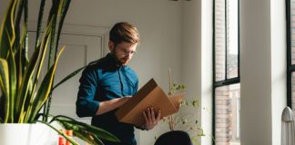 a man standing in an office holding a box
