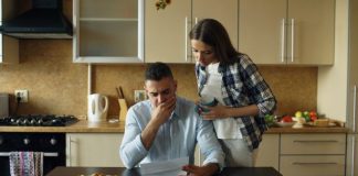 Couple looking stressed over bills at kitchen table.