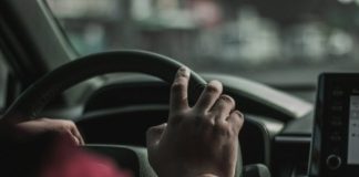a person driving a car with their hand on the steering wheel