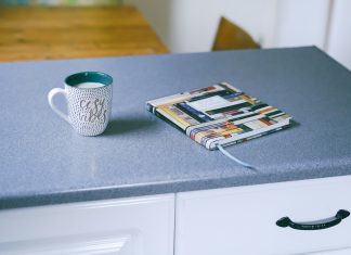 gray and white ceramic mug beside multicolored covered book