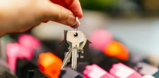 Hand holding house keys over miniature houses