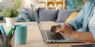 Person typing on a laptop at a wooden desk.