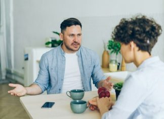 a man sitting at a table talking to a woman