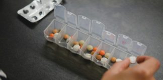 person about to pick medicine from medicine organizer