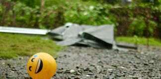 A smiley face ball sitting on a gravel road