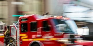 a red fire truck driving down a street next to a tall building