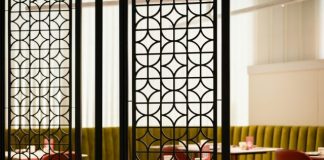 A room divider in a restaurant with red chairs