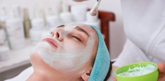 woman lying on blue towel with white cream on face