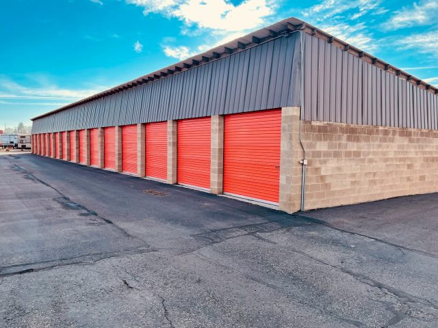 Photo by Adam Winger a storage building with red doors and a sky background
