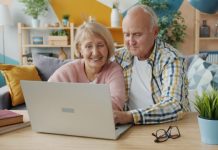 The Retirement Shift: Why Downsizing Early Helps You Live Bigger Later Elderly couple smiling while looking at laptop together.