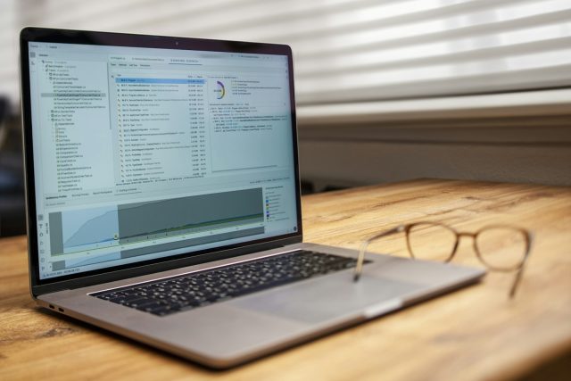 Laptop and glasses on a wooden desk.