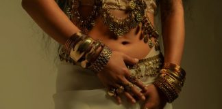 Woman wearing ornate gold jewelry and white fabric.