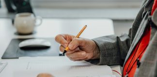 a person sitting at a desk writing on a piece of paper