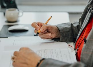 a person sitting at a desk writing on a piece of paper