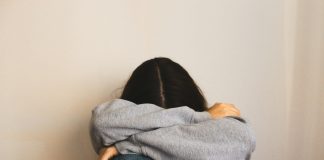 a woman sitting on the floor with her arms wrapped around her head