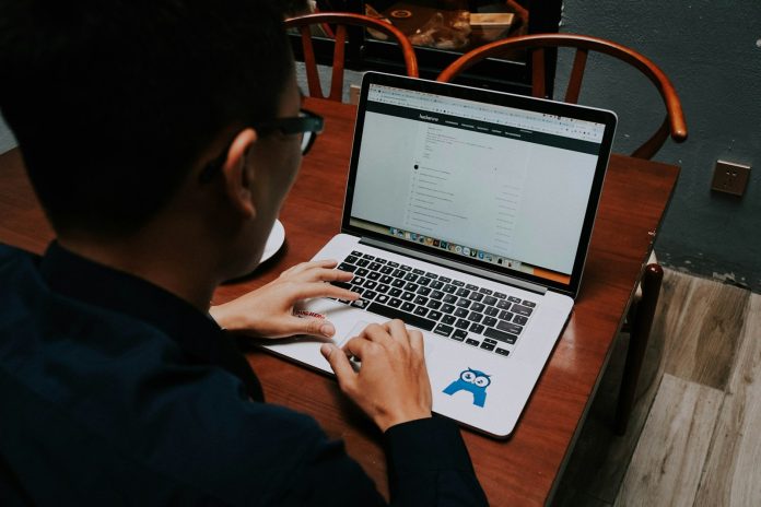 a man sitting at a table using a laptop computer