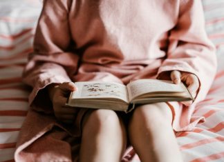 Essential Milestones Every Kid’s Story Book Should Include person reading book sitting on red and white striped bedspread