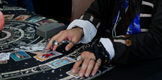 Hands arranging tarot cards on a celestial patterned cloth.