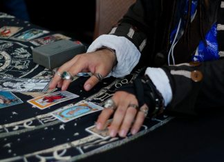 What Truly Defines a Premium Psychic Reading (And Why the Label Is Often Misused) Hands arranging tarot cards on a celestial patterned cloth.