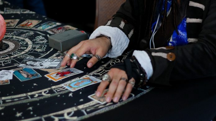 Photo by Les Taylor Hands arranging tarot cards on a celestial patterned cloth.
