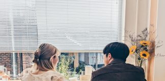 a man and a woman sitting at a table in front of a window