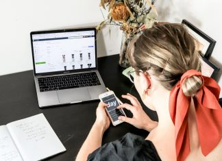woman in orange shirt using iphone