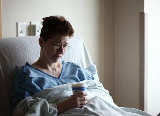 woman on bed holding plastic cup