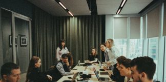 a group of people sitting around a table with laptops