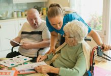 Caregiver assisting elderly couple with coloring