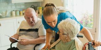 Caregiver assisting elderly couple with coloring