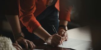 person in orange long sleeve shirt writing on white paper