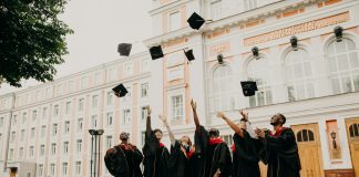 people in black academic dress standing on green grass field during daytime