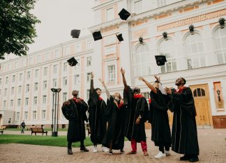people in black academic dress standing on green grass field during daytime