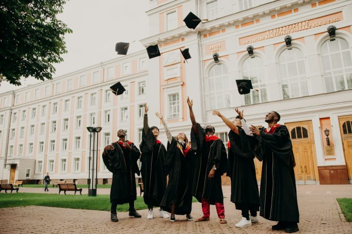 Photo by RUT MIIT people in black academic dress standing on green grass field during daytime
