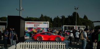 a red car parked in front of a white fence