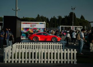 a red car parked in front of a white fence