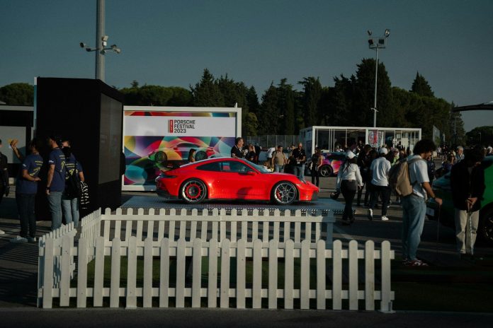 a red car parked in front of a white fence