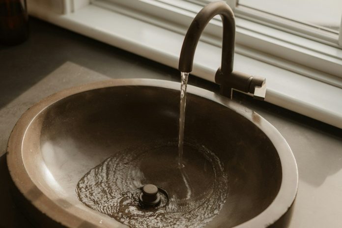 Water flowing into a bronze sink basin.