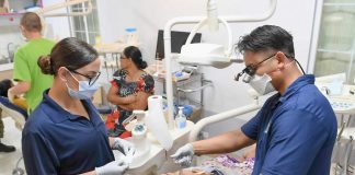 Dentists examine a patient's teeth in a clinic.