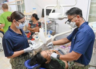 Dentists examine a patient's teeth in a clinic.