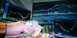 A person holding money in front of a computer screen
