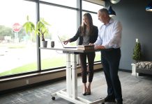 a man and a woman standing at a desk in front of a window
