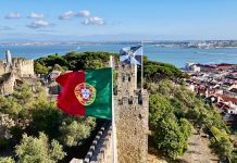 red white and blue flag on gray concrete building near body of water during daytime