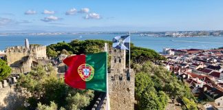red white and blue flag on gray concrete building near body of water during daytime