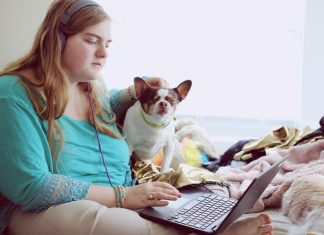 girl in blue jacket holding white and brown short coated puppy