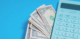 Us dollar bills and a calculator on blue background