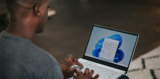 man in gray long sleeve shirt using Windows 11 computer
