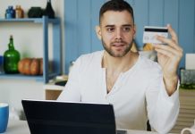 Man holding credit card while looking at laptop